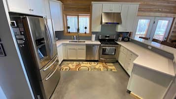 A modern kitchen with stainless steel appliances, white cabinetry, and a patterned floor.