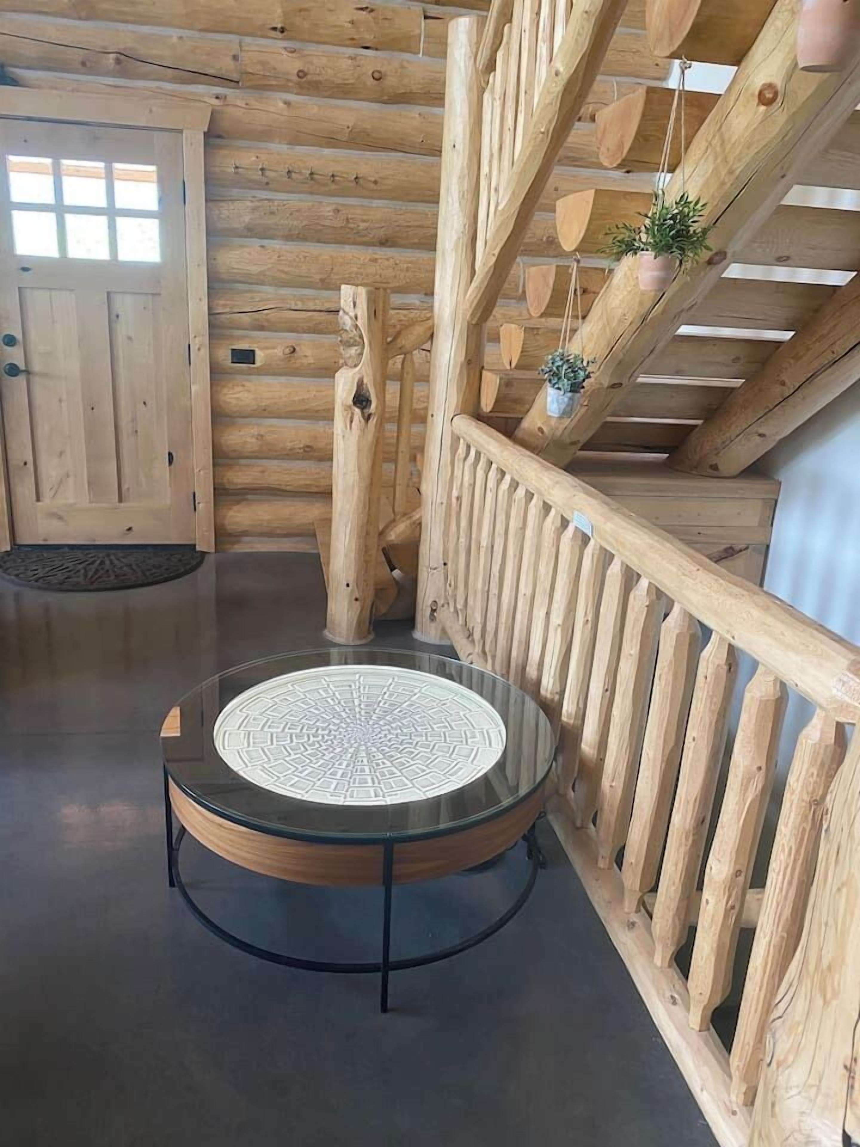 Un intérieur en bois avec une table en verre, une rambarde en bois et un escalier.