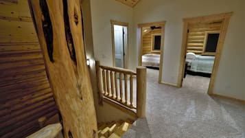 A wooden interior with a staircase leading to a bedroom with a bed and a ceiling fan.