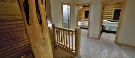 Een houten interieur met een trap die leidt naar een slaapkamer, met een bed en een plafondventilator.