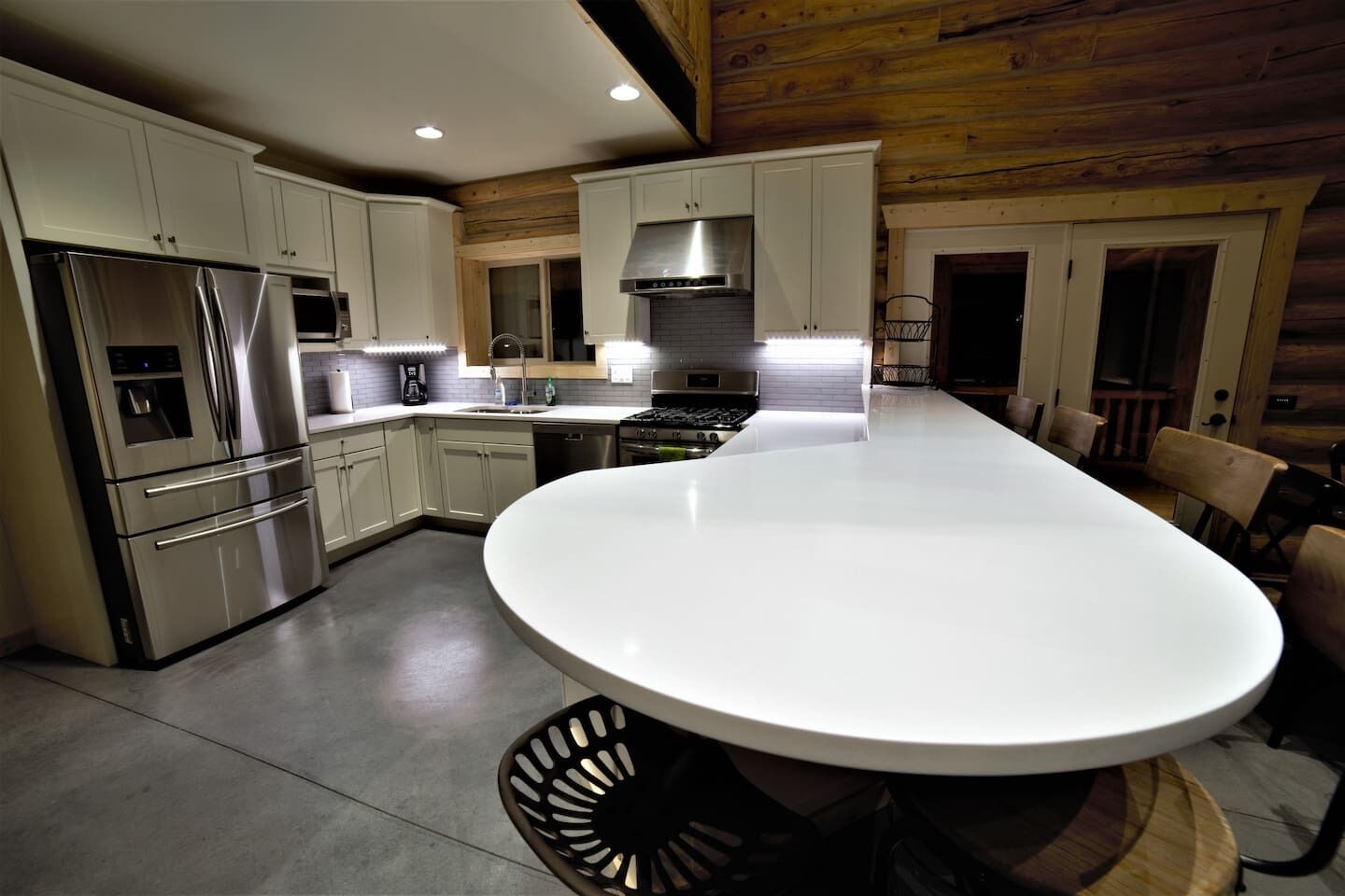 A modern kitchen with stainless steel appliances, a central island, and wooden paneling on the ceiling.
