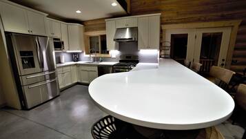 A modern kitchen with stainless steel appliances, a central island, and wooden paneling on the ceiling.