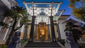 A modern building with a glass entrance, stone lion statues, and a traditional Chinese gate. - LiuHeYunYan Hotel.Dali (Dali)