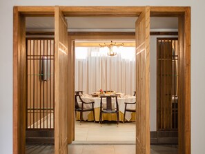 A dining area with a table set for four, surrounded by chairs, in a room with wooden sliding doors and a chandelier. - LiuHeYunYan Hotel.Dali (Dali)