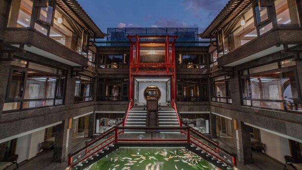 A multi-level building with a central staircase, a koi pond at the bottom, and traditional architectural elements. - LiuHeYunYan Hotel.Dali (Dali)