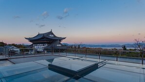 A traditional Chinese building with a pagoda-style roof, a glass-roofed terrace, and a view of distant mountains. - LiuHeYunYan Hotel.Dali (Dali)