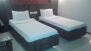 Two single beds with wooden headboards in a hotel room. - Hotel Eden (Ahmedabad)