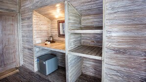 Ein kleines Zimmer mit Holzwandverkleidung, einer kleinen Küchenzeile und einer fest installierten Heizung.