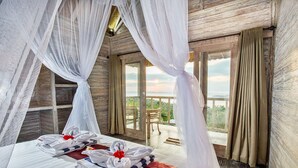 Ein Zimmer mit einem Bett, einer roten Tagesdecke und Blick ins Freie.