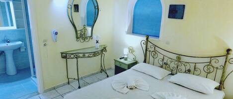A bedroom with a bed, a bedside table, a mirror, and a window.
