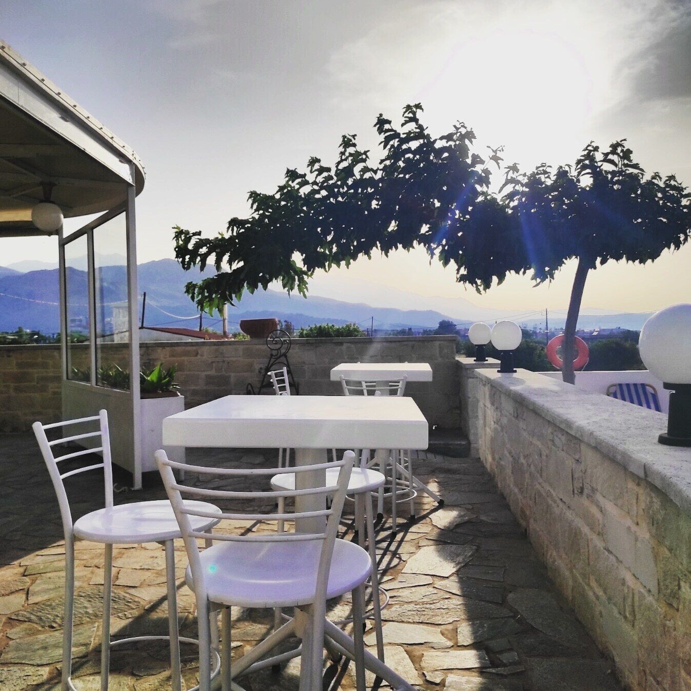 An outdoor patio with a table and chairs, a stone wall, and a view of mountains.