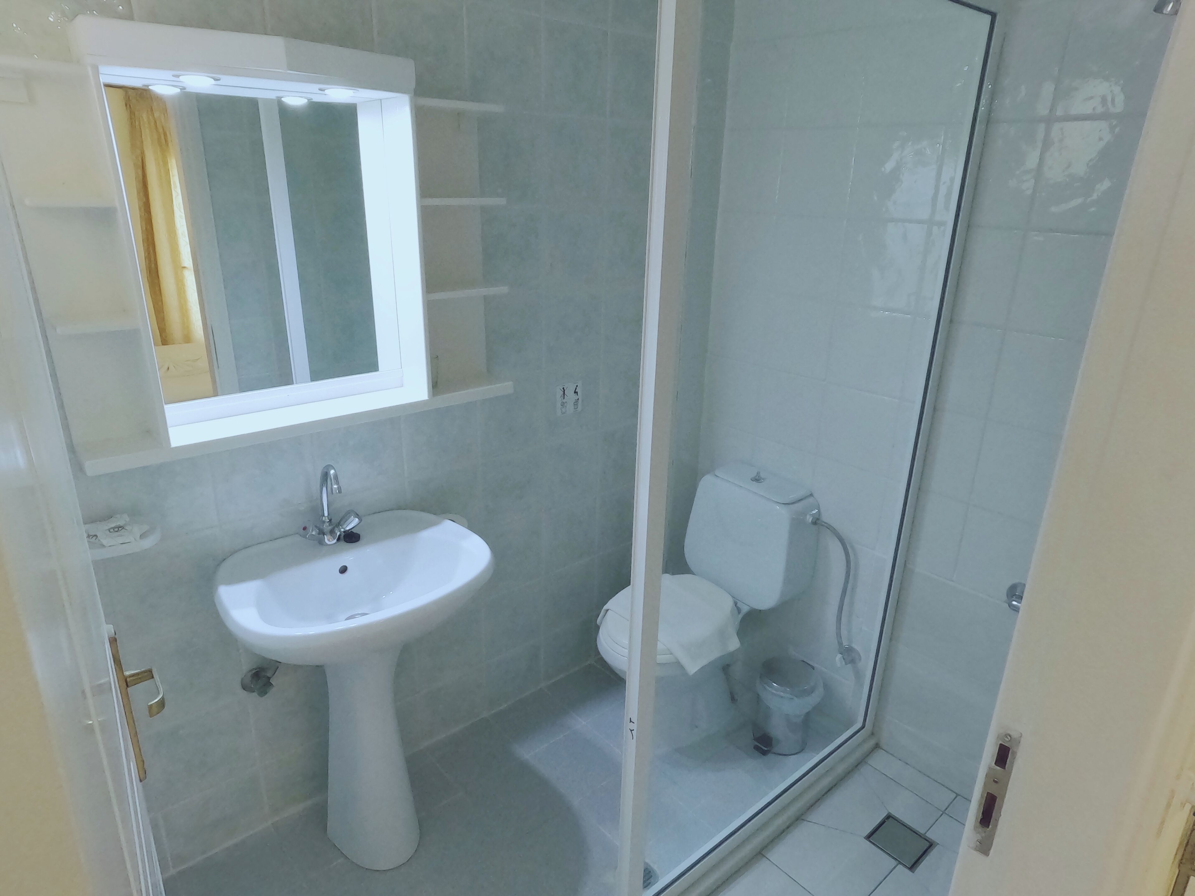 Et badeværelse med et håndvaskesæt, toilet og en bruseniche.