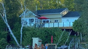A lakeside house with a dock, outdoor seating, and a covered area. - Lake Joseph 3 Bedroom Cottage and Bunkie (MacTier)