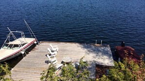 A dock with a boat, lounge chairs, and a small table. - Lake Joseph 3 Bedroom Cottage and Bunkie (MacTier)