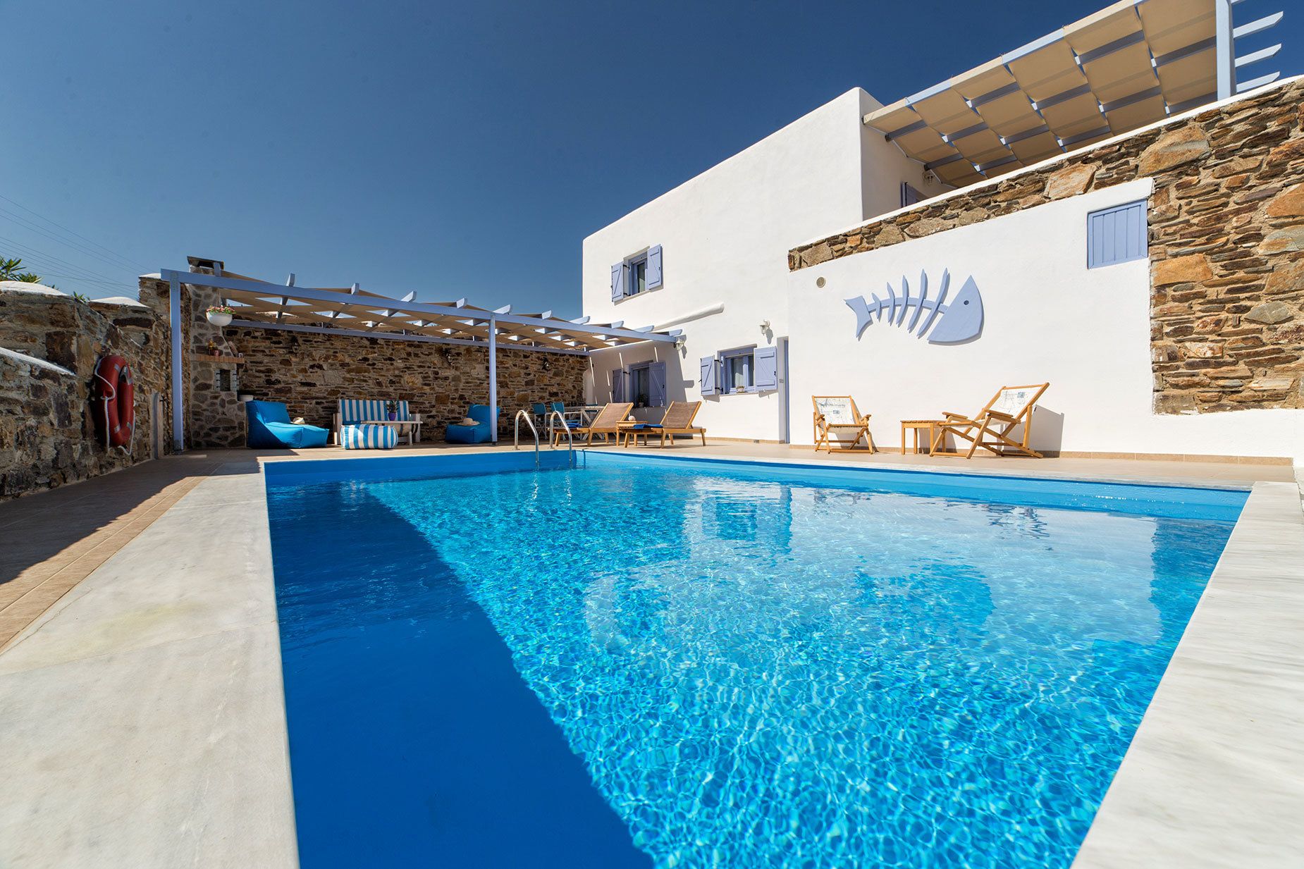 A swimming pool with lounge chairs and a stone wall.