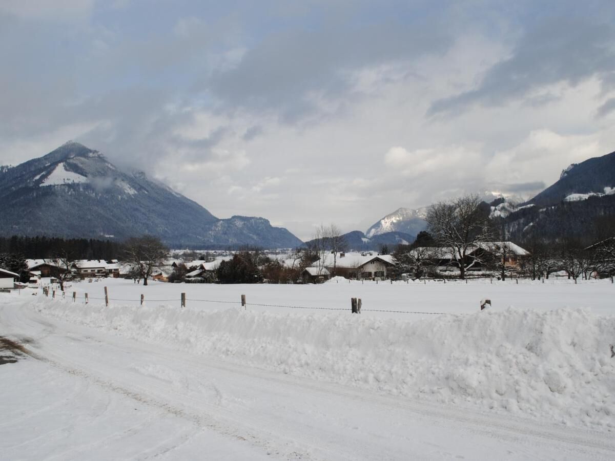 A snow-covered landscape with houses and mountains in the background.