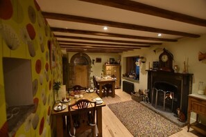 A dining area with a wooden table and chairs, a fireplace, and a patterned wall.