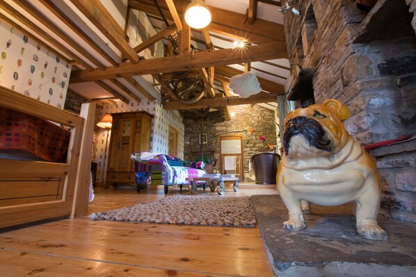 A rustic interior with exposed wooden beams, a stone fireplace, and a pug statue.