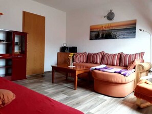 Una sala de estar con un sofá, una mesa de centro, una estantería y un cuadro en la pared.