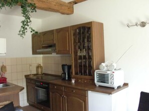 Una cocina con armarios de madera, estufa, cafetera y tostadora.