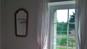 A room with a large sliding glass door to a garden, a radiator, and a framed mirror on the wall.