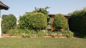 A well-maintained garden with a brick pathway, neatly trimmed grass, and various shrubs and trees.
