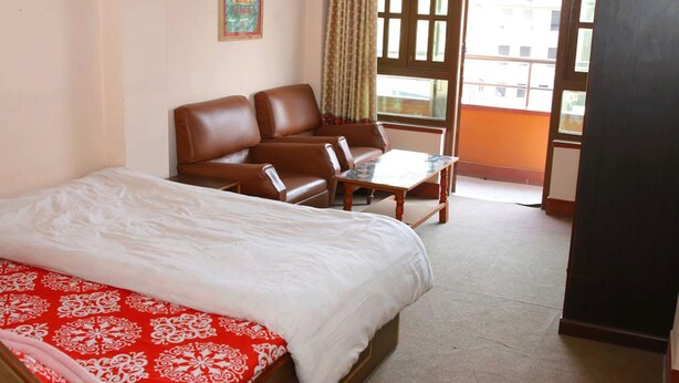 Habitación de hotel con cama, sofá, una mesita y vista al exterior a través de una ventana.