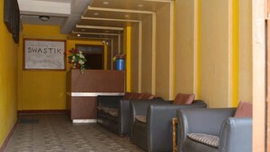 Un área de recepción con un cartel que dice “Welcome to Swastik Guest House”, un mostrador de recepción y varios sofás de cuero.
