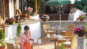 An outdoor patio area with wicker furniture, stone walls, and potted plants. - (21) Two-room vacation apartment 50 sqm, bathroom/WC, kitchen, balcony (Reit im Winkl)