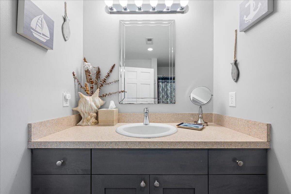 Un bagno con lavandino, specchio e oggetti decorativi sul ripiano.