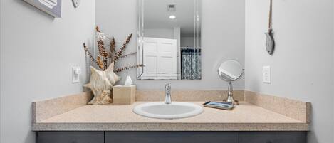 Un bagno con lavandino, specchio e oggetti decorativi sul ripiano.