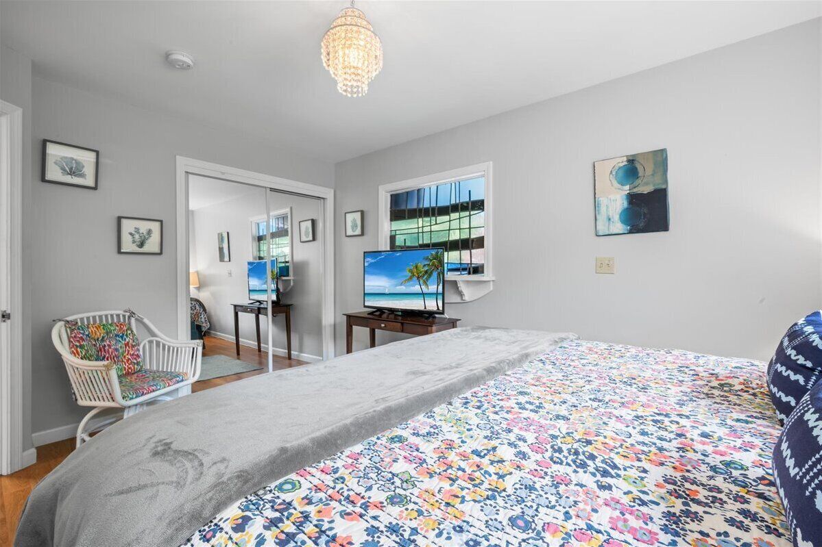 A bedroom with a bed, a television, a chair, and artwork on the walls.
