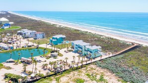 Un complejo turístico en la costa con varias construcciones, piscina y vistas a la playa.