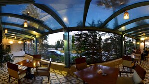 A restaurant with a glass ceiling, tiled floor, and indoor plants. - Guest House Amman (Amman)