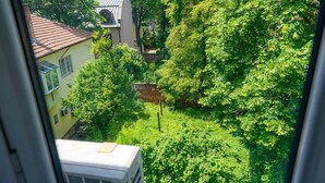 A view of a lush green garden with a building in the background. - Raya Maisonette (Sofia)