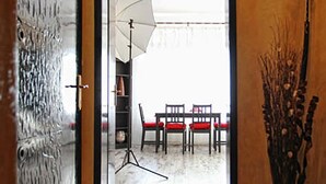 A hallway leading to a dining area with a table and chairs, a tripod with a light, and a decorative vase. - Raya Maisonette (Sofia)