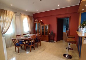 A dining area with a wooden table and chairs, a cabinet with glass doors, and a bar stool. - Agiokampos Luxurious Resort (Istiaia-Aidipsos)