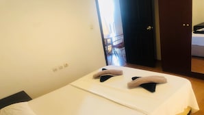 Una habitación de hotel con una cama, una mesita de noche y una puerta que da a un baño.