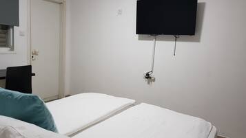 A room with two beds, a TV mounted on the wall, and a door.