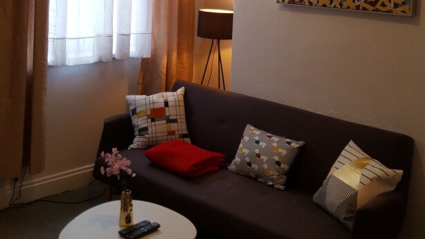 Ein Wohnzimmer mit einem dunklen Sofa, einem weißen Couchtisch, einer Stehlampe und einem Kronleuchter.