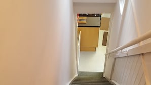 Eine Teppichstufen Treppe mit Handlauf, die zu einem Zimmer mit Bett und Fenster führt.
