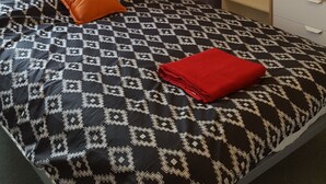 Ein Schlafzimmer mit einem Bett, einem Nachttisch, einer Ablagefläche und einer Wandleuchte, dekoriert mit Ziergegenständen.