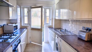 Una cocina compacta equipada con estufa, microondas, lavadora y tostadora.