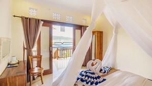 A hotel room with a bed, a chair, a desk, and a view of the sea. - Kastapar Bridge Guest House (Lembongan Island)