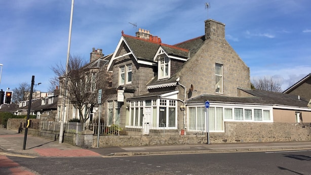 A two-story stone building with a traditional architectural style, featuring a prominent chimney and a large window on the ground floor. - Brentwood Villa Bed and Breakfast (Aberdeen)