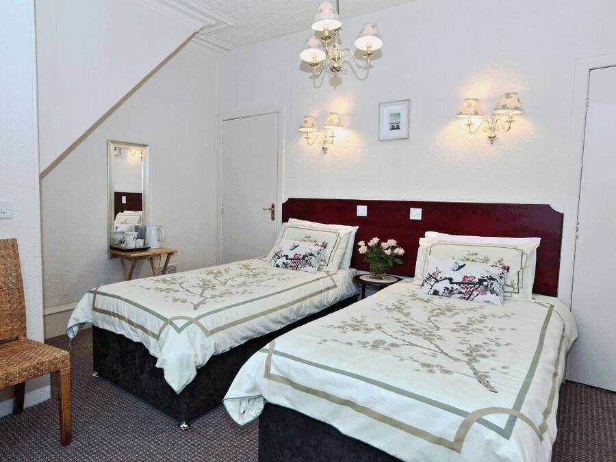A hotel room with two beds, a chair, a small table, and a mirror.