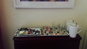 A tray with assorted chocolates and a white mug on a table against a textured wall. - Brentwood Villa Bed and Breakfast (Aberdeen)