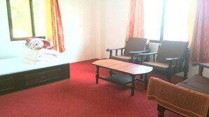 Una habitación con cama, una mesa de madera, dos sillas y una ventana con cortinas.
