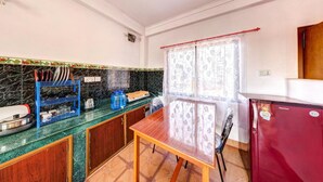 Una cocina compacta con una mesa de madera, un refrigerador y un dispensador de agua azul.