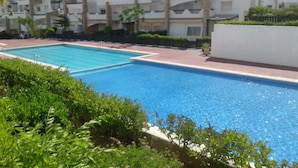 A swimming pool surrounded by greenery and modern apartment buildings. - Al Cudia Smir Beach Resort (Fnideq)